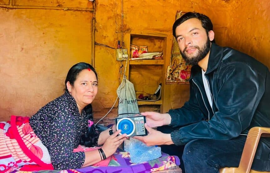 Jamuna, in bed at home in Nepal, receives a solar-powered radio from a member of the Afno FM team